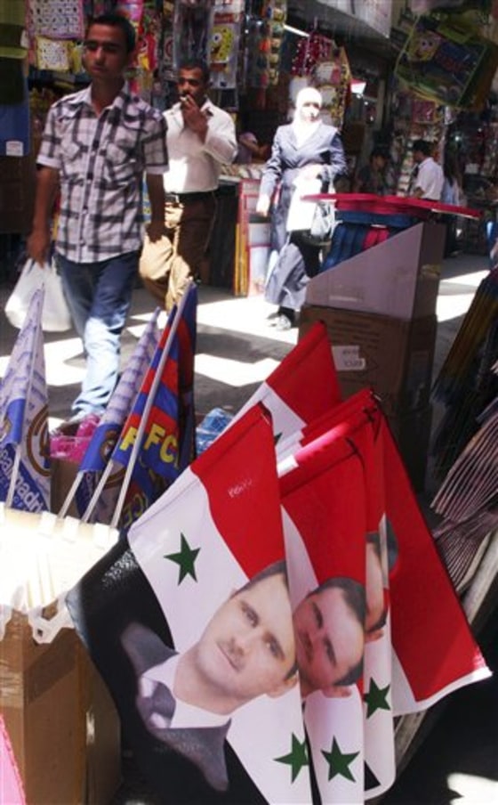 Syrians pass flags with portraits of Syrian President Bashar Assad at a popular market in downtown Damascus&nbsp;on Monday.